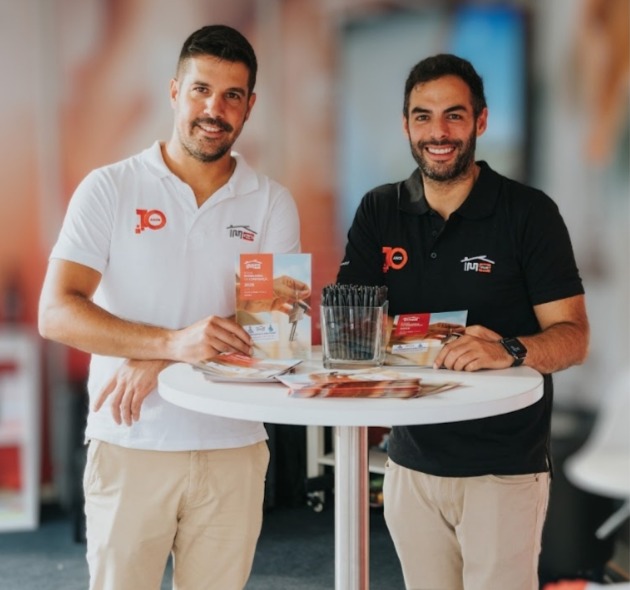 Dois consultores da Imotrust apresentam materiais do franchising Imotrust durante um evento, promovendo oportunidades de negócio imobiliário.